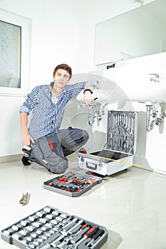 Portrait of male plumber fixing a sink in bathroom