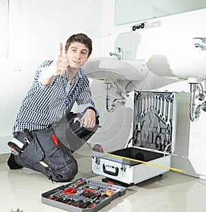 Portrait of male plumber fixing a sink in bathroom