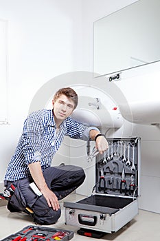 Portrait of male plumber fixing a sink in bathroom