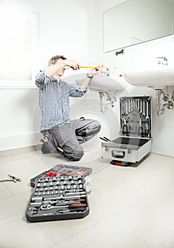 Portrait of male plumber fixing a sink in bathroom