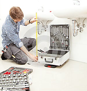 Portrait of male plumber fixing a sink in bathroom