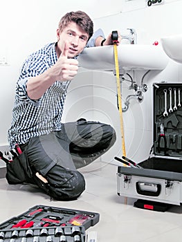 Portrait of male plumber fixing a sink in bathroom