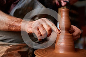 Portrait of a male potter in apron molds bowl from clay, selective focus, close-up