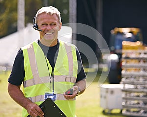 Portrait Of Male Production Worker Setting Up Outdoor Stage For Music Festival Or Concert