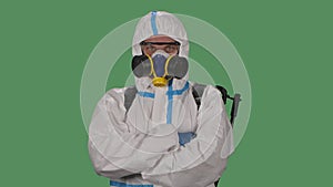 Portrait male in a protective suit, safety glasses, gloves and a respirator looks confidently into the camera and then
