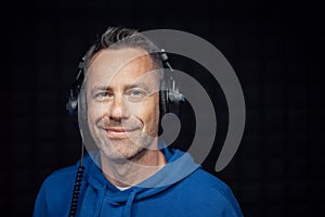 Portrait of male radio host with headphones in studio, looking at camera.