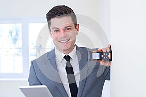 Portrait Of Male Realtor With Digital Tablet Measuring Room With Laser Measure