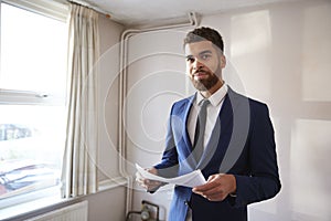 Portrait Of Male Realtor Looking At House Details In Property For Renovation