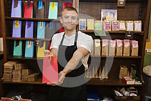 Portrait of male salesperson showing product in coffee store