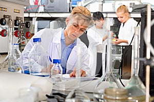 Portrait of male scientist registering results of research in notebook at biochemical laboratory