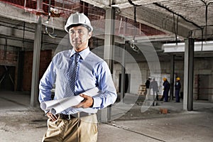 Portrait of a male site manager with blueprint at site