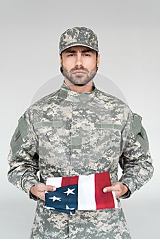 portrait of male soldier in military uniform with american flag in hands photo