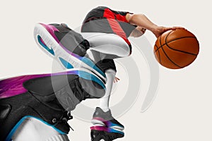 Portrait of male streetball player wearing sport uniform and doing workout with ball over white background