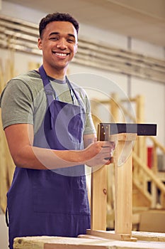 Portrait Of Male Student Studying For Carpentry Apprenticeship At College Using Set Square