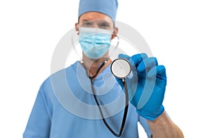 Portrait of male surgeon wearing face mask holding stethoscope against white background