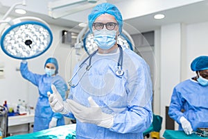 Portrait of male surgeon wearing surgical mask in operation theater at hospital. Healthcare workers in the Coronavirus Covid19