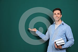 Portrait of male teacher with books on color background