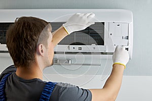 Portrait of a male technician repairing an air conditioner with a screwdriver