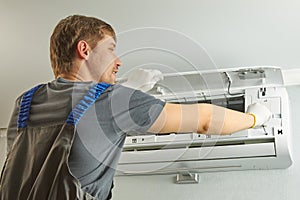 Portrait of a male technician repairing an air conditioner with a screwdriver