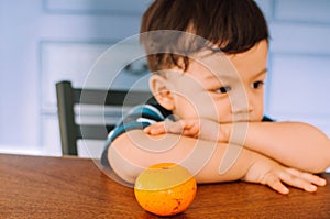 A portrait of a male toddler with orange fruit