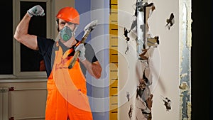 Portrait of male worker in uniform and respirator with huge hammer on his shoulder looking at camera with serious eyes