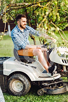 Portrait of male worker using lawn tractor for cutting grass