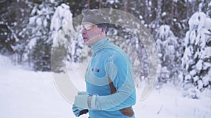 Portrait of a man 40 years old, running through the winter forest