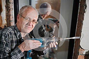 Portrait of a man 55-60 years old in a working environment during the repair of an apartment with his own hands, in a