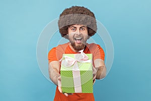 Man giving gift, congratulating on birthday and offering surprise, holiday bonus wrapped in box. photo