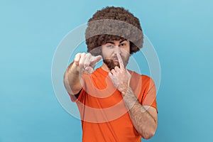 Man touching nose, showing liar gesture, angry about falsehood, pointing to camera fake news. photo