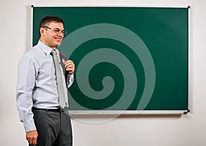 Portrait of a man as a teacher, posing at school board background - learning and education concept