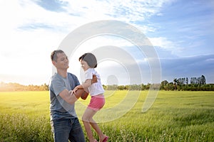 Portrait of a man and Asian Thai kid girl , father and daughter having fun playing outdoors. which the father takes good care of