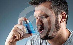 Portrait of a man with an asthma inhaler in his hands, an asthmatic attack. The concept of treatment of bronchial asthma, cough,