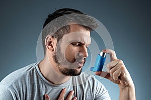 Portrait of a man with an asthma inhaler in his hands, an asthmatic attack. The concept of treatment of bronchial asthma, cough,