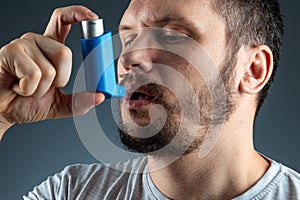 Portrait of a man with an asthma inhaler in his hands, an asthmatic attack. The concept of treatment of bronchial asthma, cough,