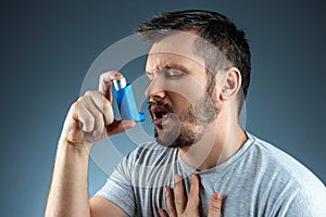 Portrait of a man with an asthma inhaler in his hands, an asthmatic attack. The concept of treatment of bronchial asthma, cough, photo