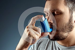 Portrait of a man with an asthma inhaler in his hands, an asthmatic attack. The concept of treatment of bronchial asthma, cough, photo