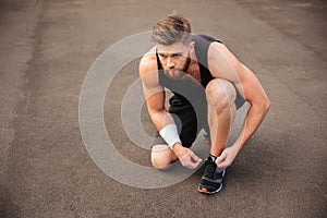 Portrait of man athlete ties his shoelaces