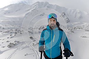 Portrait of man backcountry skier hiking to the summit of a snowy peak in the Low Tatras in Slovakia.