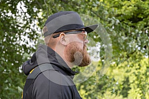 Portrait of a man with a beard 30-35 years old wearing glasses for shooting against the background of nature.