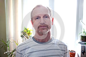 Portrait of a man with beard, aged mature years. Standing indoors by the window