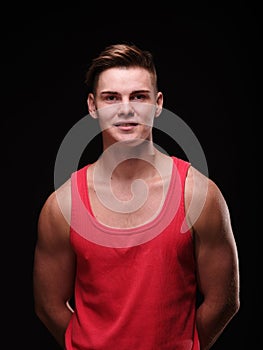 Portrait of a man on a black background in a red tank top.