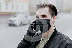 Portrait of a man in a black medical mask. Coronavirus. A man is talking on the phone