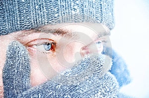 Portrait of a man with blue eyes against a background of falling snow. Beautiful snowy weather. Snowing. Selective focu