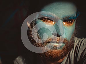 Portrait of a man with a blue make-up on his face. Stage make-up, like an alien, fantasy.