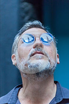 portrait of a man with blue sunglasses looking up