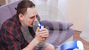 Portrait of a man breathing through an inhaler mask at home.Treatment of pulmonary diseases. copy space