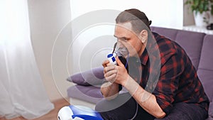 Portrait of a man breathing through an inhaler mask at home.Treatment of pulmonary diseases. copy space