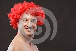 Portrait of a man in a bright red curly wig, funny facial expressions, on the background