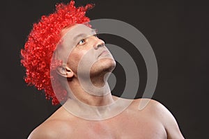 Portrait of a man in a bright red curly wig, funny facial expressions, on the background